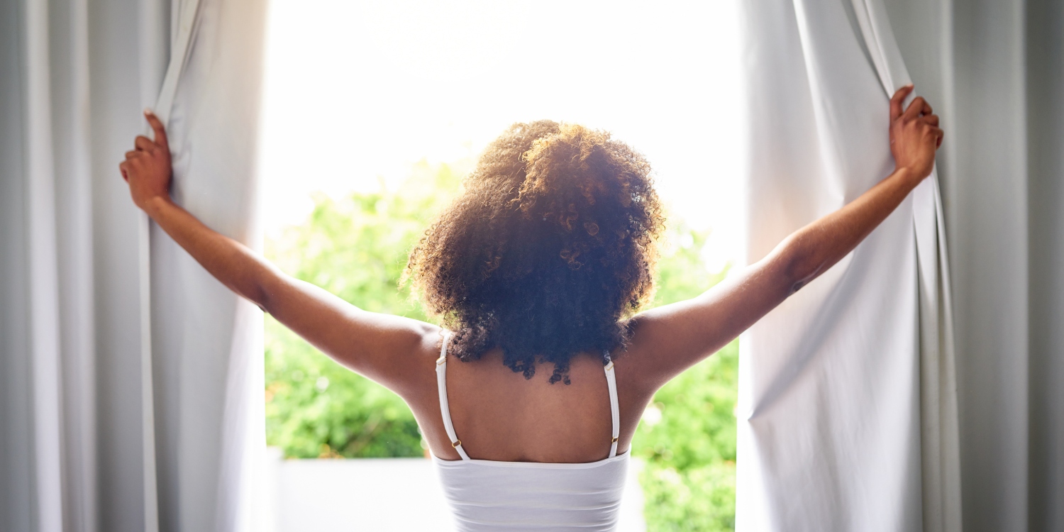 woman looking out window in morning sunlight