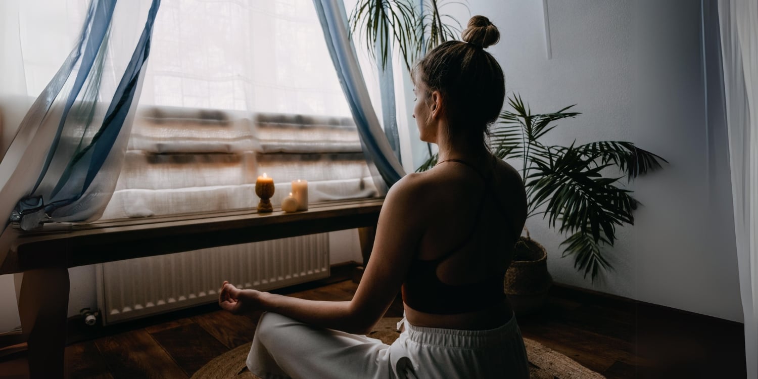 woman seated and meditating facing window
